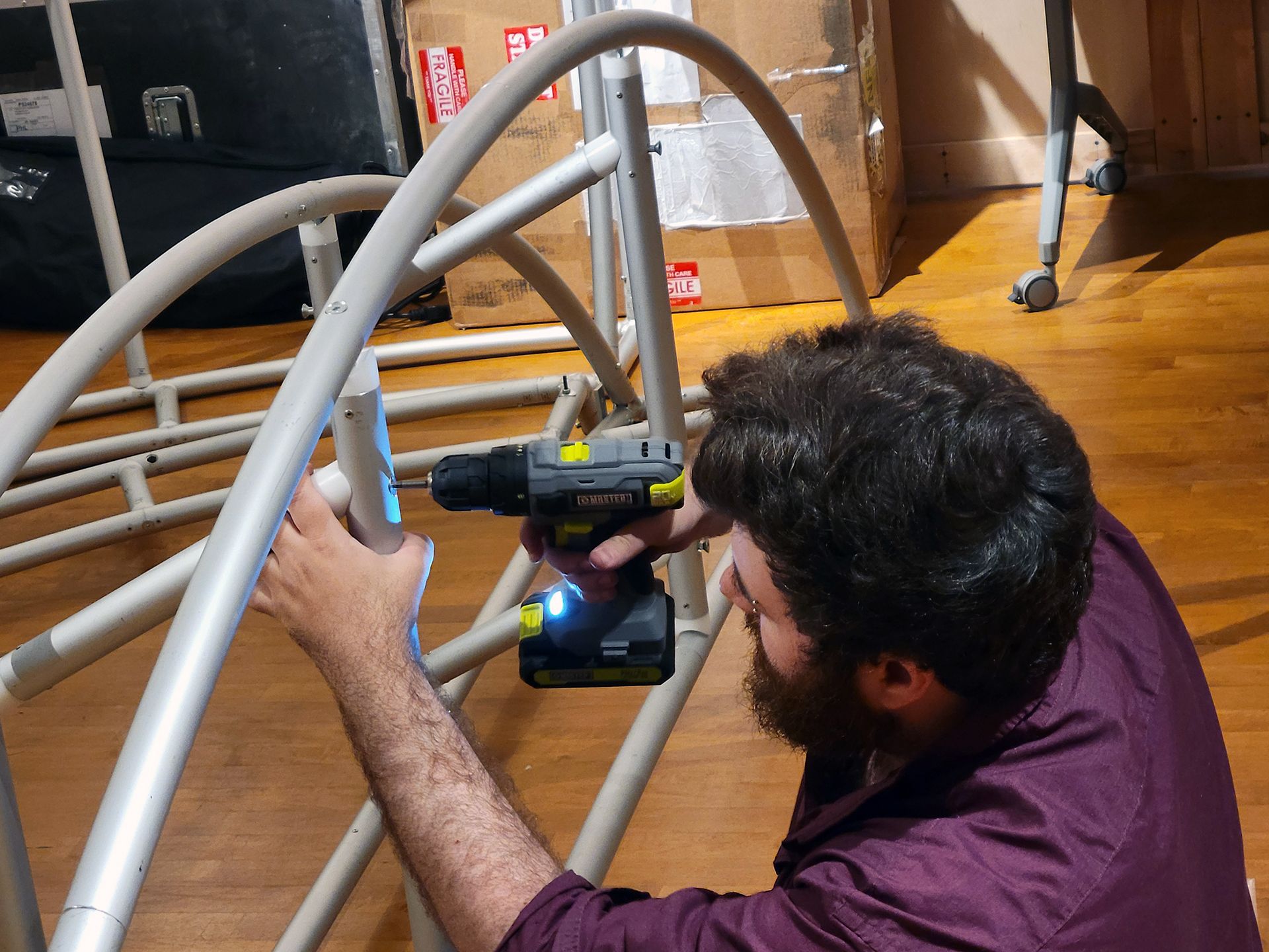 man assembling dome frame using power driver